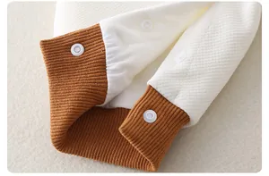 Detail of baby romper with caramel ribbed cuffs, waffle texture, and snap buttons