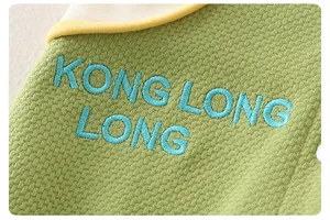 Detail of green cotton baby romper with waffle texture and blue letter embroidery