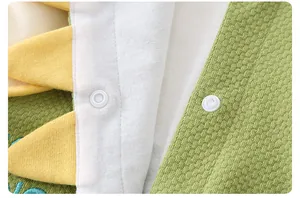 Detail of baby romper featuring green waffle knit fabric and white snap closures