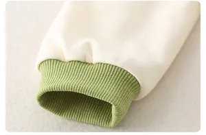 Close-up of baby romper cream fabric with soft green ribbed cuffs and knitting detail