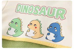 Detail of dinosaur print and yellow piping on soft cotton baby bodysuit fabric