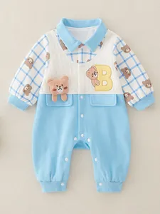 Blue baby romper with cartoon bear embroidery and checkered sleeves on flat lay background