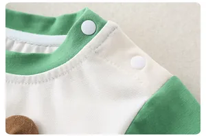 Detail of infant bodysuit neckline with green trim and convenient shoulder snap buttons