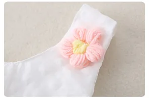 Detalle de tela jacquard blanca con una flor de punto rosa en el tirante del hombro