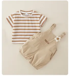 Detalle de conjunto infantil con camiseta a rayas y peto marrón con bordado de sonrisa