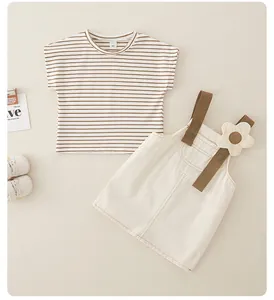 Detalle de camiseta de algodón a rayas y vestido de tirantes beige con una pequeña flor