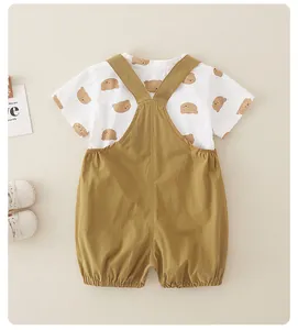 Détail à plat d'un ensemble bébé en coton avec T-shirt imprimé ours et salopette moutarde