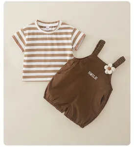 Detalle de camiseta de rayas para bebé y peto smile marrón con adorno de flor suave