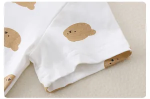 Détail de la manche d'un t-shirt bébé en coton blanc avec motif ours brun
