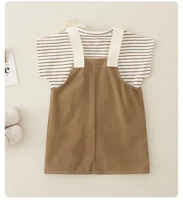 Plano detalle de camiseta a rayas para bebé y vestido marrón sobre alfombra suave