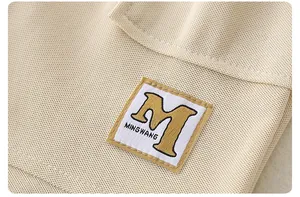 Vista detallada del tejido de algodón beige con parche del logo MINGWANG en bolsillo