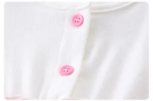 Macro shot of breathable white knit fabric featuring vibrant pink decorative buttons
