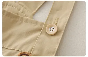 Détail macro de la salopette bébé avec boutons aspect bois et broderies en peluche douce