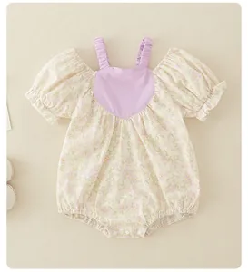 Detailed view of floral baby romper with purple heart chest patch and ruffled straps