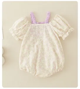 Detailed close-up of baby floral romper featuring purple ruffled straps and puff sleeves