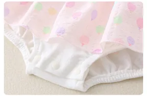 Detail of baby bodysuit featuring snap button closure and pink balloon print fabric