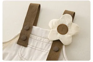 Detalle del vestido de tirantes de algodón para niña con tiras trenzadas y flor decorativa