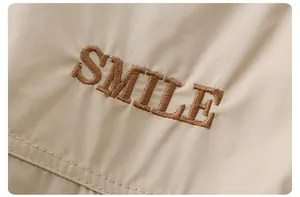 Vista macro detallada del bordado SMILE en ropa de algodón beige para niños pequeños