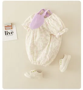 Flat lay of a floral baby romper with purple straps and matching cream canvas shoes