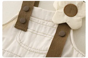 Detalle del vestido de tirantes en algodón beige con correas marrones y bordado floral