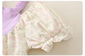 Detail of baby summer romper featuring purple fabric and floral print with ruffle sleeves