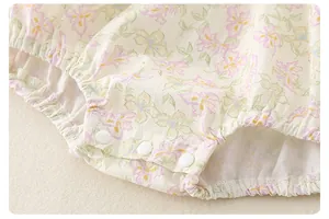 Close-up of floral baby bodysuit featuring snap buttons and elastic leg openings