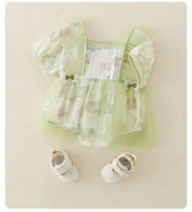 Detail van baby romper met bloemen, groene tule en witte leren babyschoentjes