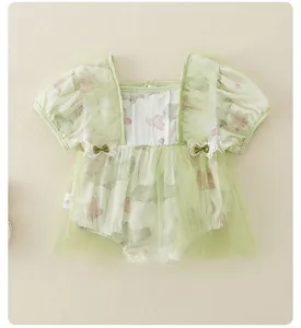 Detail van babyromper met bloemenprint, laagjes tule en decoratieve strikjes
