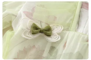 Detailopname van groene babyromper met bloemenprint, mesh en kanten vlinderdecoratie