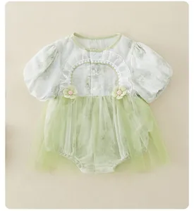 Dettaglio tutina neonata con maniche a sbuffo, colletto in pizzo e gonna in tulle verde