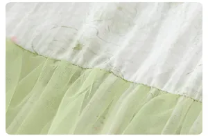 Dettaglio cuciture abito neonata con tessuto testurizzato bianco e tulle a rete verde