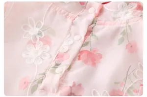 Close-up of pink floral baby romper featuring white flower embroidery and snap buttons
