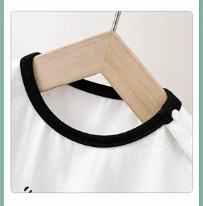Detail of white cotton baby bodysuit with black crew neck and shoulder snap buttons