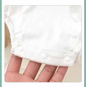 Detailed macro view of three white resin snap buttons on a soft cotton baby bodysuit