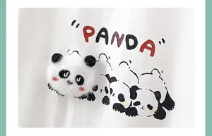 Detail of 3D plush panda patch and cartoon prints on white cotton baby bodysuit
