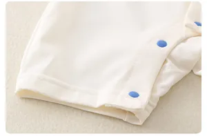 Detail of white cotton baby bodysuit showing breathable mesh fabric and blue snap buttons