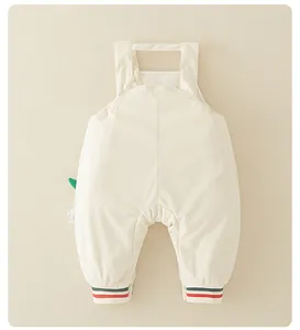 Détail d'une grenouillère bébé en tricot nid d'abeille avec poignets rayés et patch