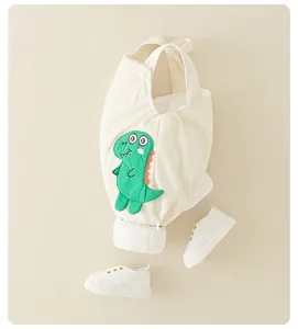 Détail de la barboteuse dinosaure avec texture gaufre beige et broderie douce