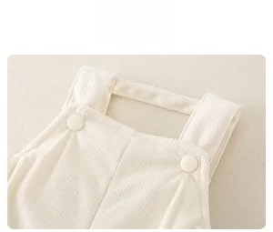 Détail des bretelles d'une barboteuse bébé en tissu gaufré avec boutons ronds