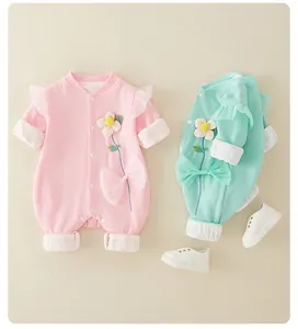 Detail of waffle knit baby rompers with floral embroidery and large ribbon accents