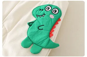 Détail macro du tricot gaufré crème avec écusson dinosaure de dessin animé vert