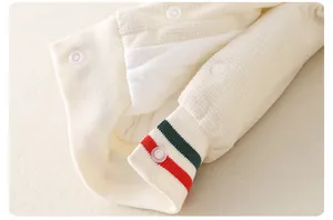 Détail du tissu gaufré d'une barboteuse bébé avec poignets rayés et boutons pressions