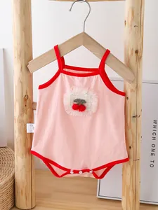 Pink cotton baby romper with cherry patch, red trim, and snap buttons on a wooden hanger