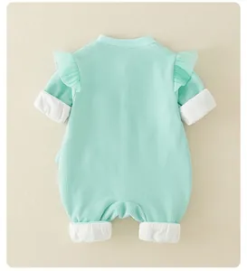 Detail of mint green waffle knit baby romper featuring ruffled shoulders and white ribbed cuffs