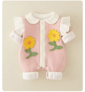 Detailed view of baby romper featuring pink waffle knit fabric and sunflower embroidery