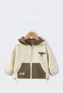 Close-up of cute cartoon dog embroidery on a beige and brown hooded children's jacket