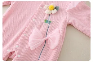 Detail of pink waffle knit baby romper with 3D floral embroidery and a large tulle bow
