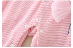 Detailed view of pink ribbed baby romper with snap buttons and mesh bow decoration
