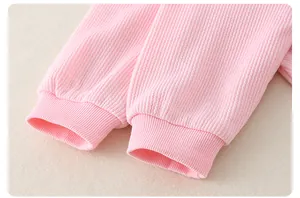 Close-up of pink waffle texture fabric and elastic ribbed cuffs on baby jumpsuit