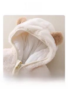 Dettaglio della tutina neonato con cappuccio in morbido peluche e orecchie da orsetto
